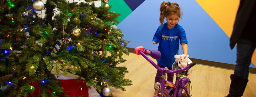 Little girl standing by her bicycle with a prosthetic arm attachment on it