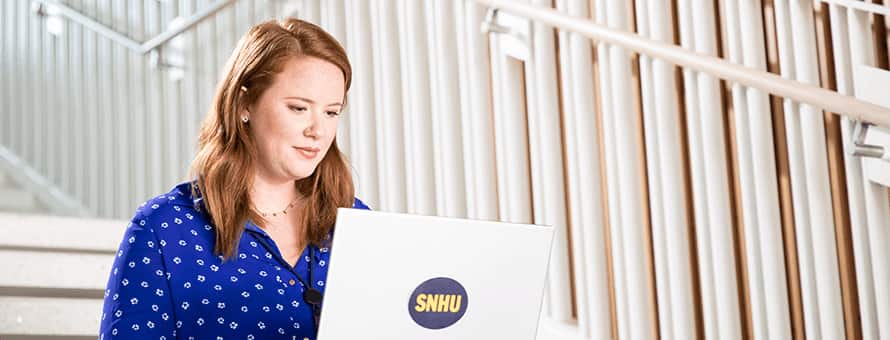 Ali Lamoureux sitting on steps while working on her SNHU laptop