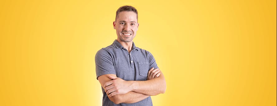 Blake Venable standing with his arms crossed in front of a yellow background 