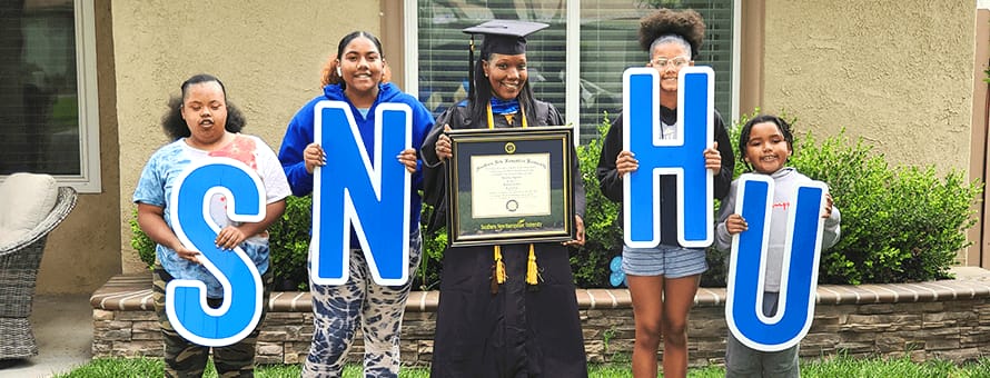 Latisha Aguilar holding her diploma with her four children Amayah, Adyrann, Avery and Aiyan each holding letters that spell out SNHU.