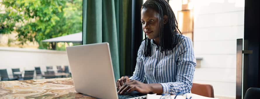 A woman sitting at a table on her laptop working towards her associate degree