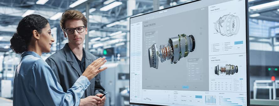An engineering manager listening to an engineer explaining machinery on a screen.