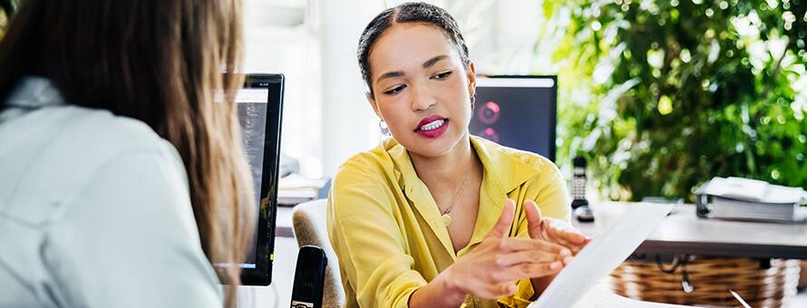 An employee holding her resume and listening to her mentor tell her how to become a manager