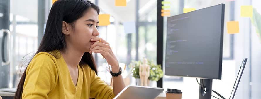 A woman looks at a computer screen studying how to become a software engineer