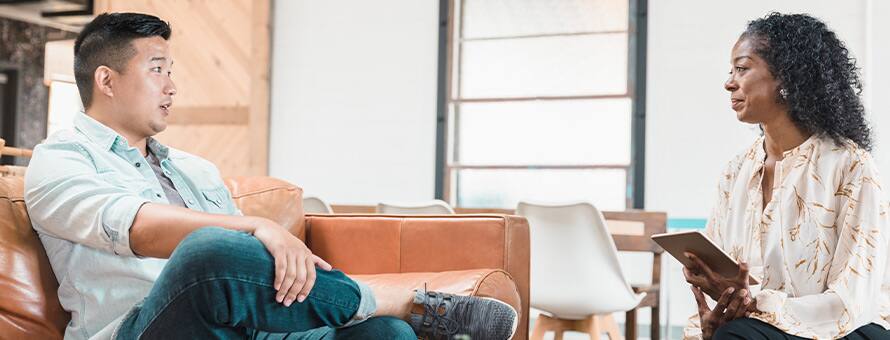 A female therapist and a male patient sitting across from one another during a sessions