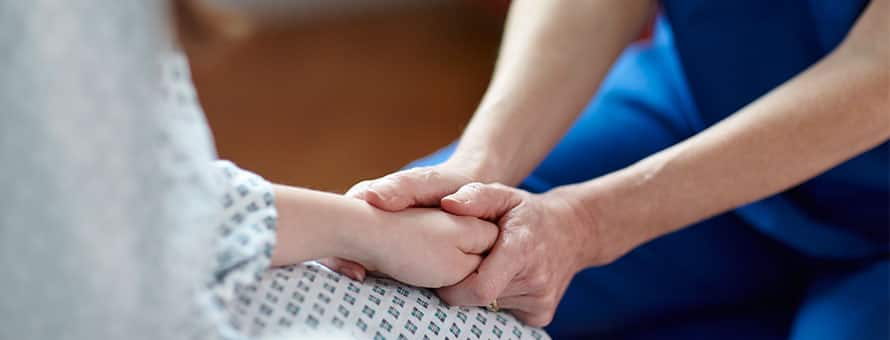 Close up of a nurse holding a patient's hand