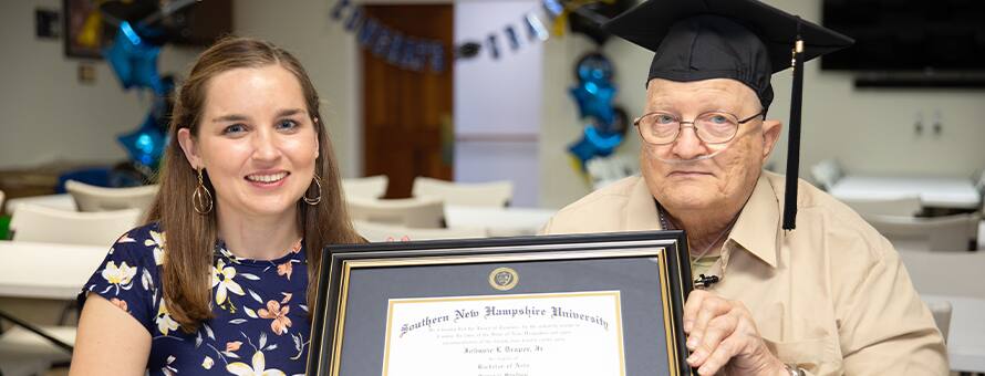 SNHU graduate John Draper holding his diploma with his advisor Courtney Hannon