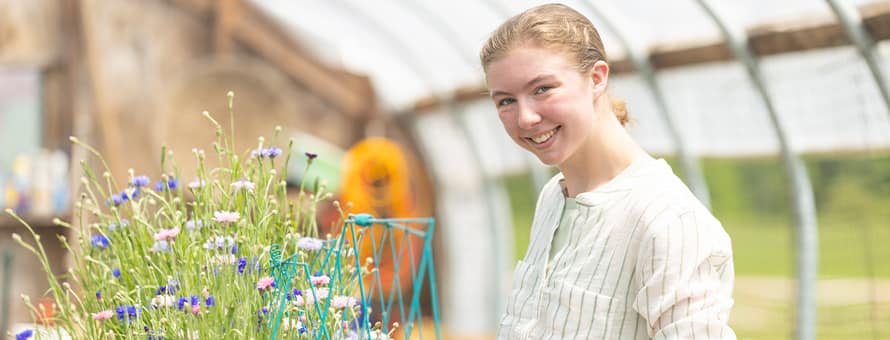 Kayla Stoll, an environmental science student at SNHU, with plants in a greenhouse.