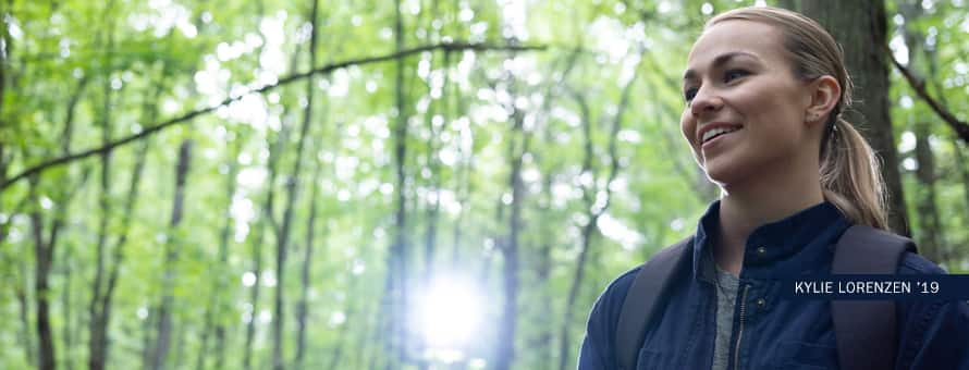 SNHU environmental science grad Kyle Lorenzen walking in a dense forest