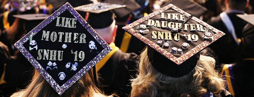 The top of the graduation caps of a mother and daughter at commencement reading Like Mother SNHU '19 and Like Daughter SNHU '19.