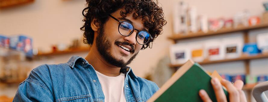 A man reading a book with a green cover.