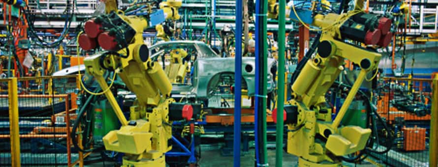 Large yellow robotics on an automobile assembly line where a manager with a technical degree might work.