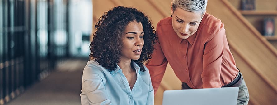 Two management accountants discussing information on one of their a laptops.