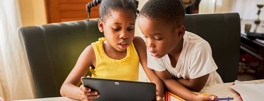 A sister and brother using a tablet for remote learning.