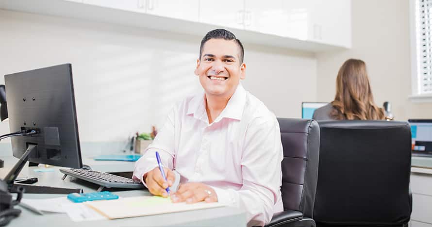 Juan Munoz, who earned his degree from SNHU in 2022, sitting in an office next to a computer.