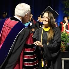 Jessica Bryant wearing cap and gown and receiving her degree from SNHU President Paul LeBlanc.
