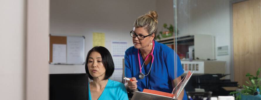 A nurse educator overlooking the work of another nurse.