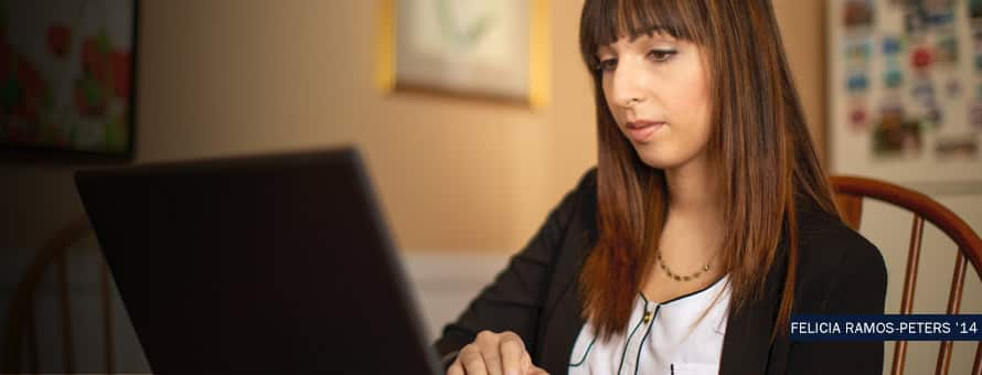 SNHU graduate, Felicia Ramos-Peters working on her computer. With the text Felicia Ramos-Peters '14