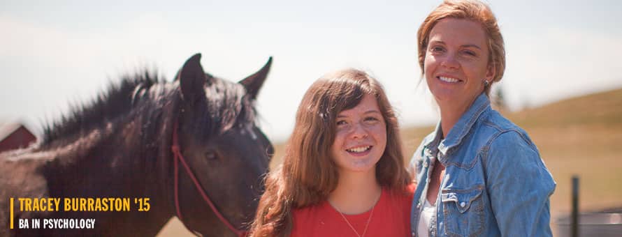 Tracey Burraston a 2015 BA in psychology graduate from SNHU and her daughter standing next to a brown horse