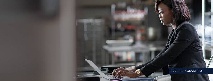 Woman working on a laptop with text "Sierra Ingram '19"