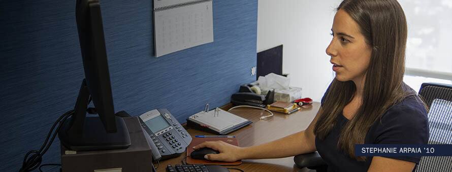 Stephanie Arpaia, who earned her online sports management degree in 2010, using a computer in an office.