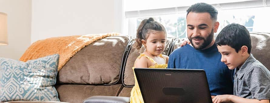 A father and his children looking at a laptop