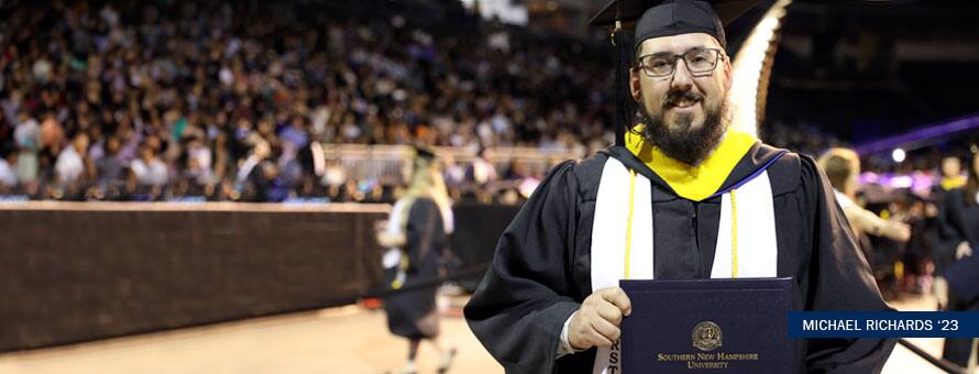 Michael Richards standing in his cap and gown after graduating with an online computer science degree with a concentration in software engineering.