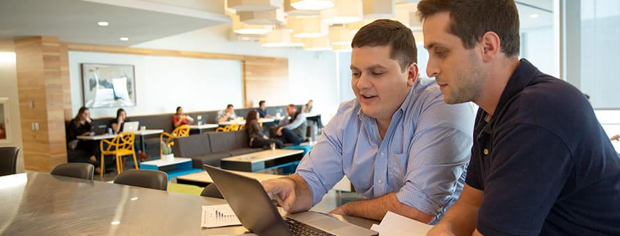 Two SNHU students working on a laptop