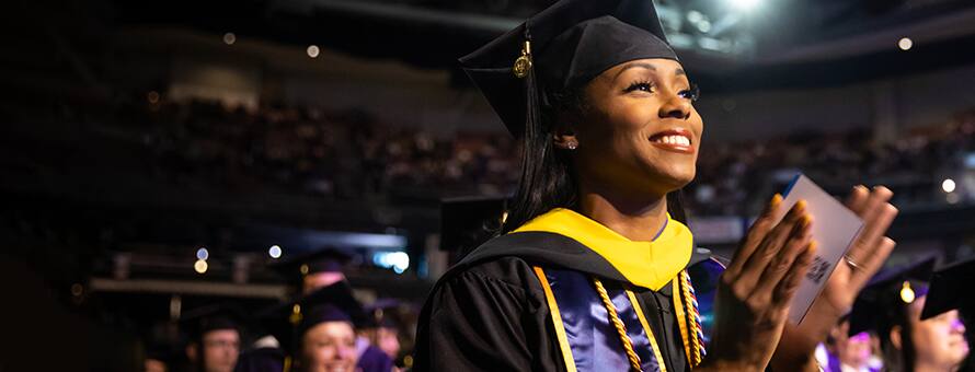An SNHU graduate celebrating at Commencement 2023 in her cap and gown
