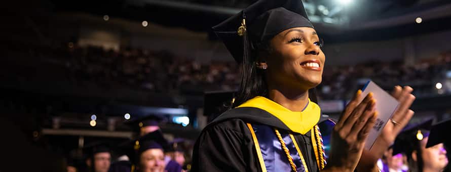 An SNHU graduate celebrating at Commencement 2023 in her cap and gown