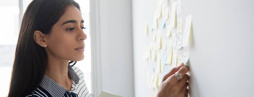 A woman reviewing her personal growth and professional development plan on sticky notes