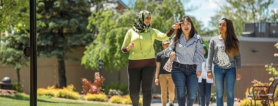 Three women walking down a path on a college campus.