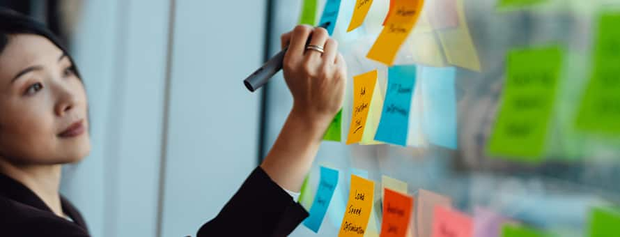 A woman writing down her short- and long-term goals for work on sticky notes