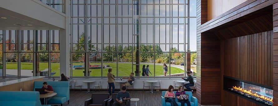 The cafe inside the Shapiro Library with students sitting at tables and in chairs in front of a huge glass wall.