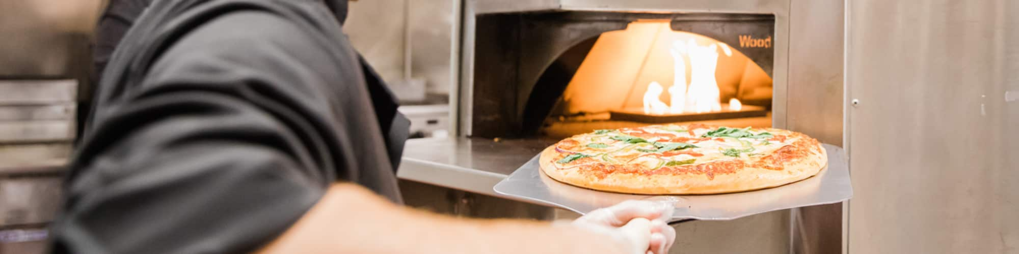 Pizza being loaded into an oven