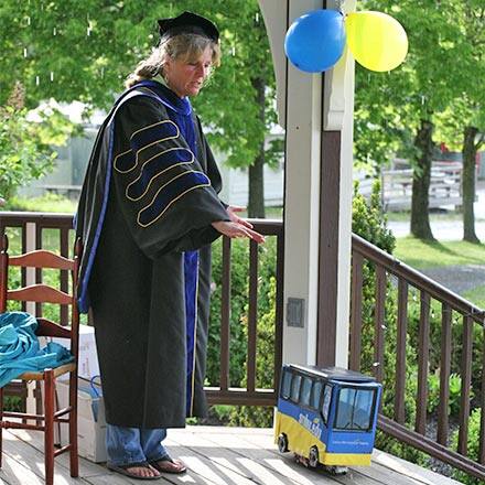 Dr. Gwen Britton and a miniature SNHU bus carrying Fiona Mathiesen's diploma.