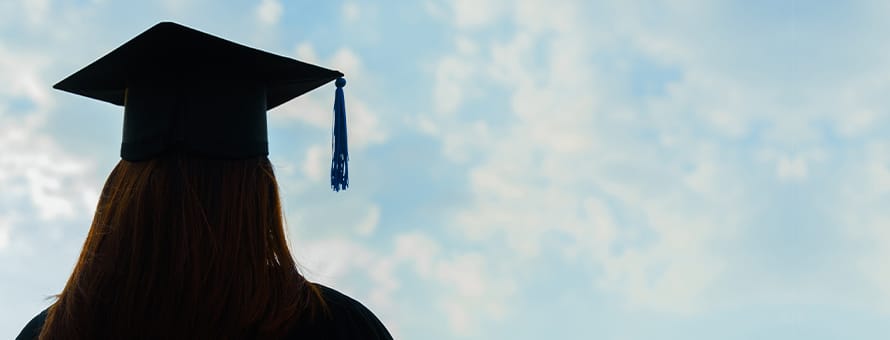 A college graduate on Military Spouse Appreciation Day, wearing her mortarboard and looking toward the sky.