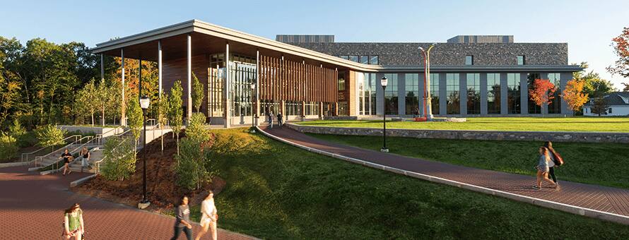 Multiple groups of students walking in front of the Library Learning Commons building on SNHU Campus.