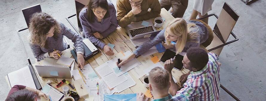 A group of students sit at a table discussing the importance of critical thinking