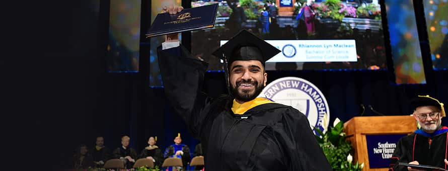 An SNHU graduate holding up his diploma at the 2019 Commencement ceremony