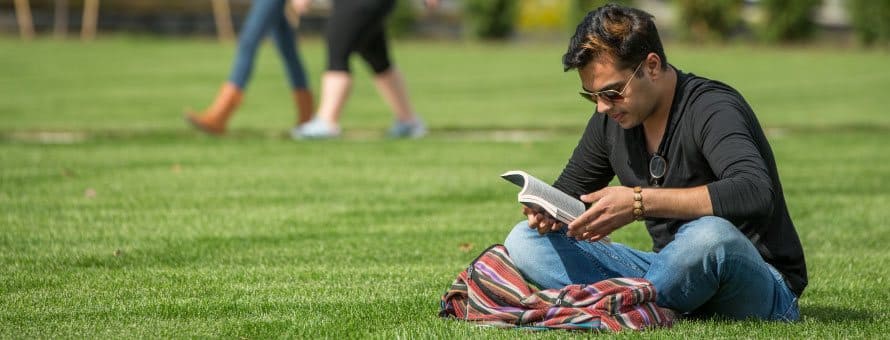 Student reading on the grass