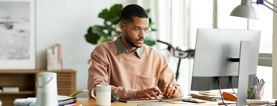 A man working on his desktop researching the types of graduate degrees