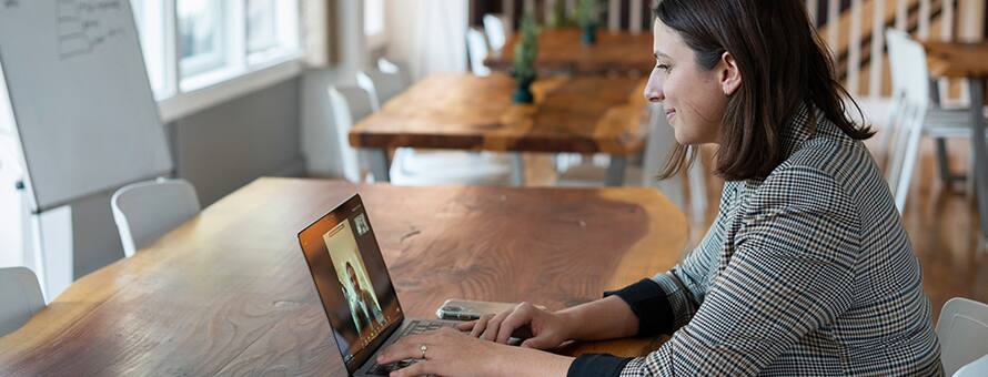 A healthcare student sitting at a table, participating in a webinar on her laptop.