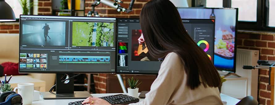 A game developer editing gameplay footage on a multi-monitor workstation.