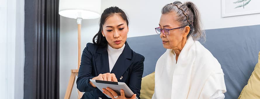 A woman sitting with a caseworker looking at an iPad