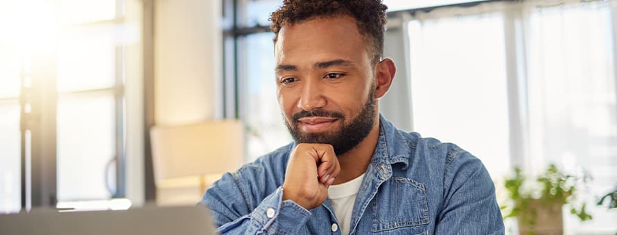 A recent college graduate on a laptop who is reading a cover letter he wrote for his resume.