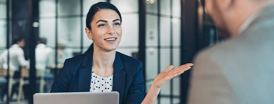 A woman sitting behind a laptop speaking to a man about HR