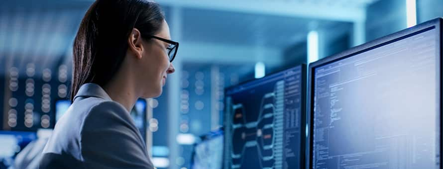 A woman sitting at a desktop working on information security 