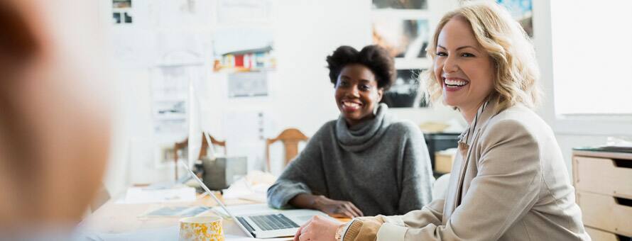 Two women with their sociology degrees sitting at a table smiling.