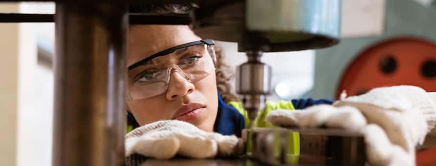 A mechanical engineer wearing protective equipment while working with machinery. 